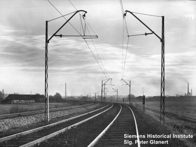 zweigleisige gerade Strecke mit Oberleitung an Streckmetallmasten mit Schr&auml;gausleger und einfachen Kappenisolatoren